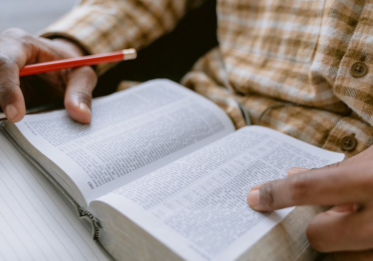 man reading bible with pencil in hand